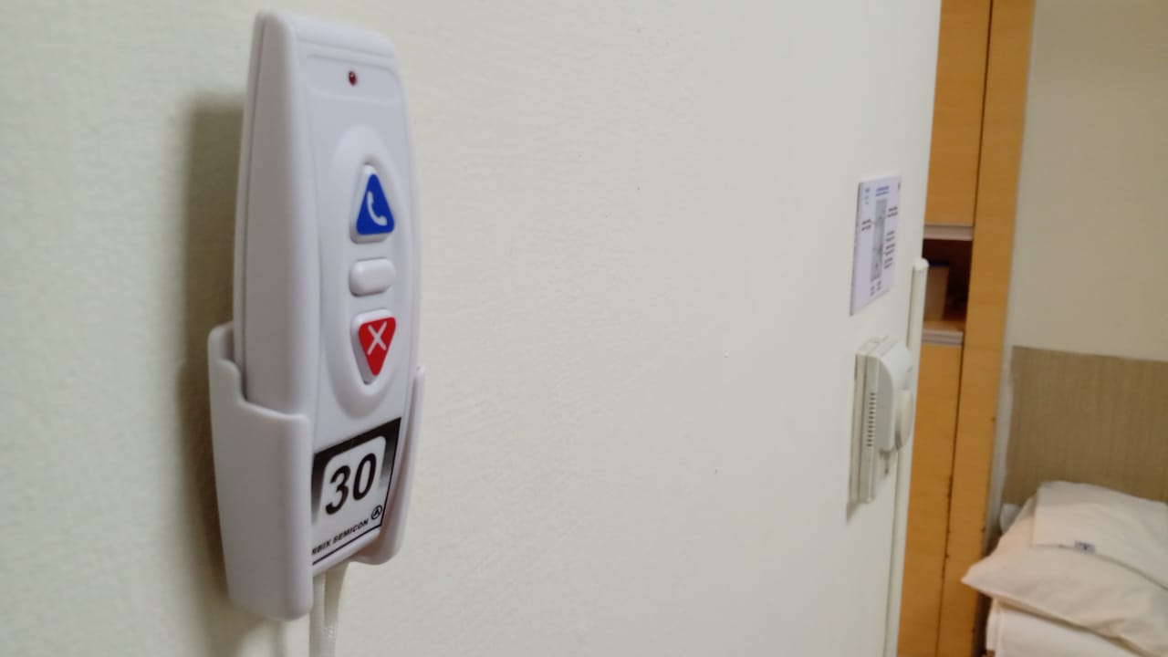 Bedside Call Button - Wall-mounted call button positioned within easy reach of patients for immediate nurse assistance.